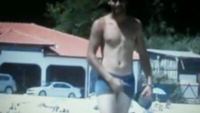 Ein heißer Kerl, der am Strand entlangläuft und sich an seiner Beule reibt